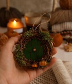 a hand holding a miniature green door in front of some pumpkins and other decorations