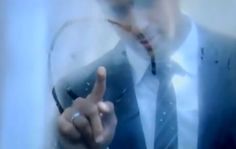 a man wearing a suit and tie making a hand gesture with his finger in front of him