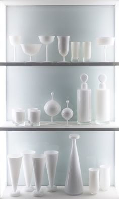 the shelves are filled with white vases and glasses