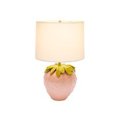 a table lamp with a white shade on it and a pink vase shaped like a flower