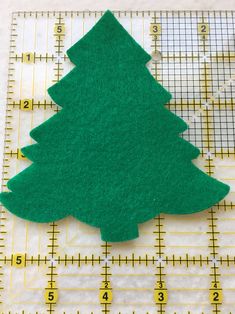 a green felt christmas tree sitting on top of a ruler