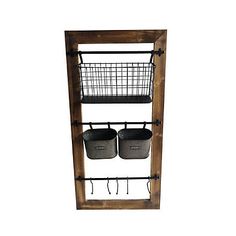 a wooden shelf with two metal baskets and hooks on the bottom, hanging from it's side