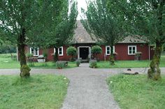 a small red house surrounded by trees and grass