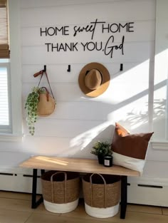 a bench with two baskets on it next to a sign that says home sweet home thank you god