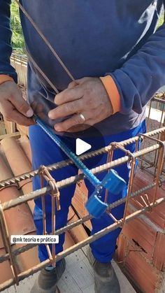 a man standing on top of a wooden floor next to a metal cage filled with pipes