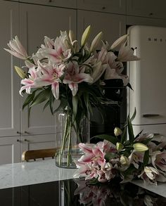 a vase filled with pink and white flowers on top of a counter next to an oven