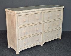 a white wicker dresser with black top