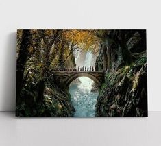 people walking across a bridge in the middle of a river surrounded by trees and rocks