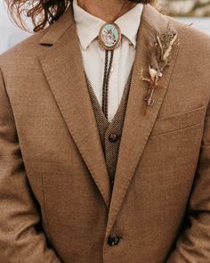 a man with long hair wearing a brown suit and white shirt is looking at the camera