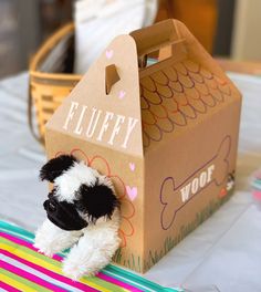 a small stuffed dog sitting in front of a cardboard box with the word fluffy on it