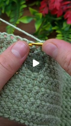 a person holding onto a green crochet bag with a tiny white triangle on it