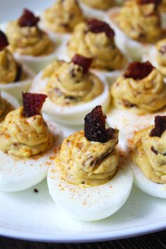 deviled eggs with bacon are arranged on a white platter, ready to be eaten