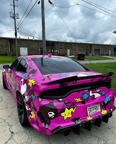 a pink sports car is parked on the side of the road with stickers all over it