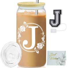 a glass jar with a straw in it next to a card and the letter j