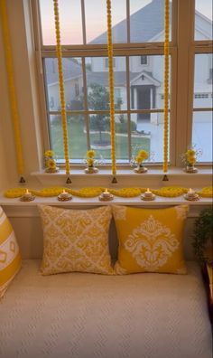 a window seat with yellow pillows and candles on it