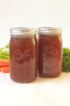 two jars filled with food sitting next to carrots and broccoli