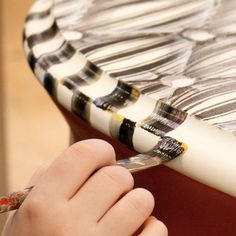 a close up of a person using a brush to paint a piece of art on a table