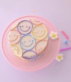 a smiley face cake sitting on top of a pink plate