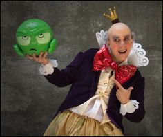 a man dressed in costume holding two green masks