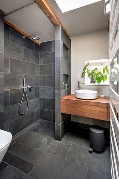 a modern bathroom with grey tile and wood accents