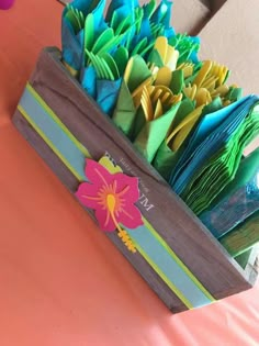 a wooden box filled with paper flowers on top of a table