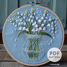 the embroidery pattern shows a vase with white flowers in it, on a blue background