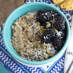 a blue bowl filled with oatmeal and blackberries