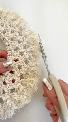 a woman using scissors to crochet a white doily