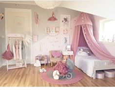 a bedroom with pink and white decor on the walls, wooden flooring and a canopy bed