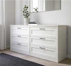 a white dresser with two drawers and a potted plant sitting on top of it