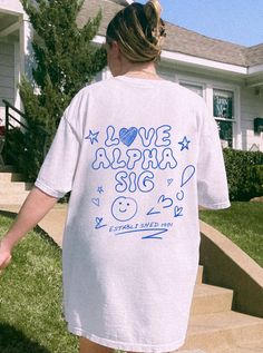 a woman is walking down the steps in front of her house wearing a white t - shirt with blue writing on it