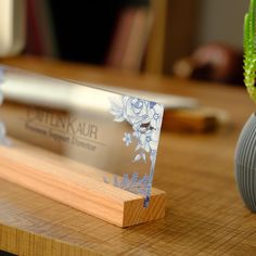 a clear business card sitting on top of a wooden table next to a succulent