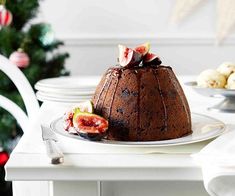 a chocolate cake on a plate with figs and christmas tree in the background,