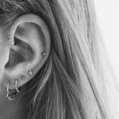 a woman's ear with three piercings on it