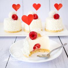 a white plate topped with a piece of cake covered in frosting and raspberries