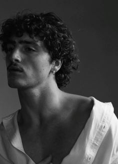 a man with curly hair wearing a white shirt