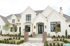 a large white house with lots of windows and bushes in front of the entrance to it