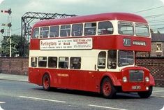 a red and white double decker bus driving down the street with power lines in the background