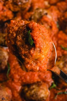 a spoon full of meatballs with tomato sauce