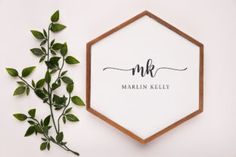 a wooden frame with the word mrk on it next to a plant and some leaves