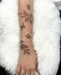 a woman's arm with butterflies and leaves on it