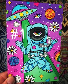 a hand holding up a card with an image of a spaceman and flowers on it