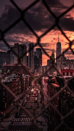 the city skyline is seen through a chain link fence at sunset in new york, usa