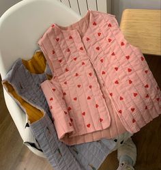 a pile of clothes sitting on top of a white chair next to a wooden table