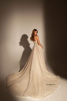 a woman in a white dress standing against a wall with her shadow on the wall