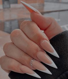 a person with long nails holding an orange and white ring