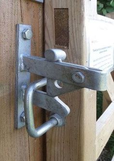 a close up of a metal latch on a wooden door with a sign in the background