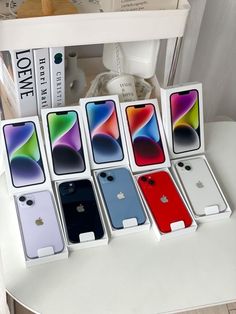 six different colored iphones are on display in their boxes, one is red and the other is blue