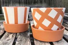 two orange and white cups sitting on top of a wooden table next to each other