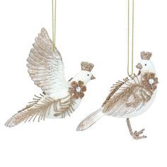 two white birds hanging from chains with gold trimmings on their wings and feet